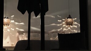 Quarto com cama, almofadas e luminária pendente.