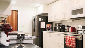 A modern kitchen with white cabinets, a black refrigerator, a coffee maker, and a red kettle. - Ideal for long stays, Near/airport GYM-Parking. (Toronto)