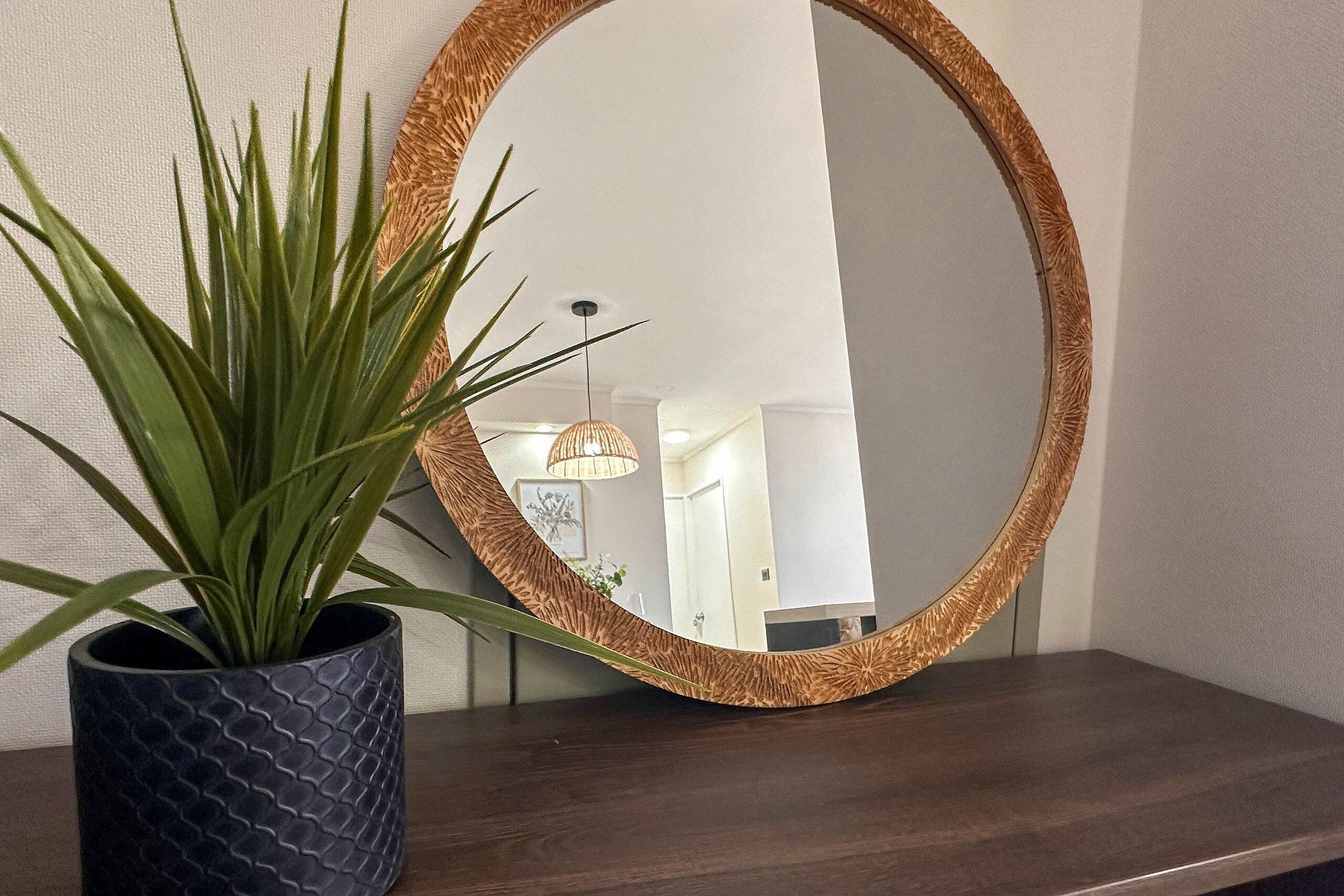 A round mirror with a woven frame on a wooden surface.