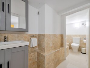 Une salle de bain moderne équipée d’un lavabo, d’un miroir, d’un porte-serviettes et de toilettes.