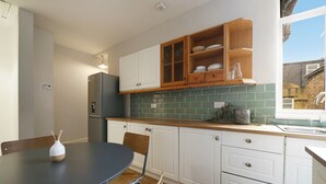 A modern kitchen with white cabinets, a wooden countertop, and a green backsplash. - Pass the Keys | Cosy apartment in Kilburn (London)