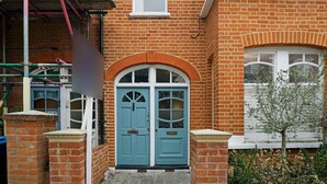A two-story brick building with a central entrance featuring a blue door with a decorative arch. - Pass the Keys | Cosy apartment in Kilburn (London)