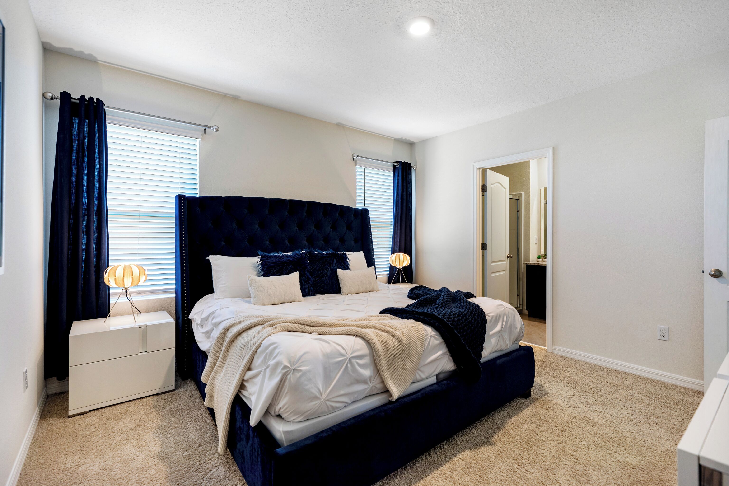A bedroom with a large bed, bedside tables, a nightstand, and a mirror.