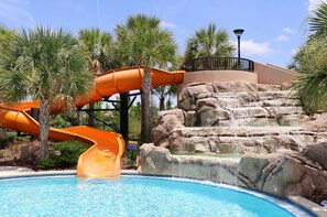 A pool with two orange slides, a rock waterfall, and palm trees. - Solterra- LakeView - Private Pool & Spa  (Davenport)