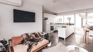 A modern living room with a sofa, a coffee table, and a TV mounted on the wall. - Pacific Sun CBD Apartment (Yamba)