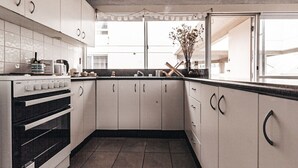 A kitchen with white cabinets, a black oven, and a window with a view of buildings outside. - Pacific Sun CBD Apartment (Yamba)