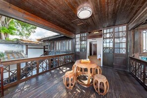 A wooden deck with a round table and stools, a railing, and a view of traditional architecture. - Juchunyuan Hotel (Fuzhou Sanfang Qixiang) (Fuzhou)