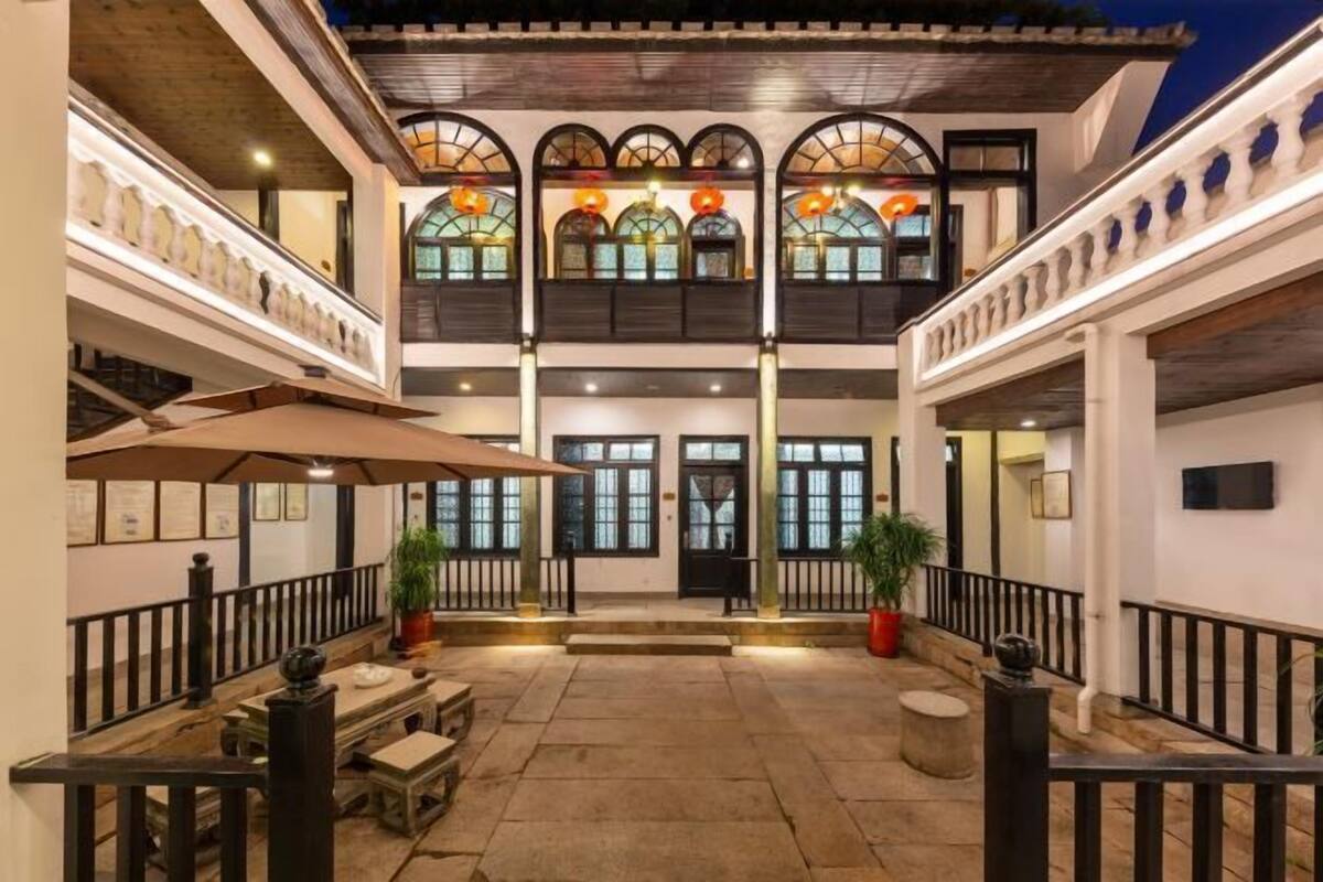 Un patio con una escalera central, plantas en macetas y una zona de estar.