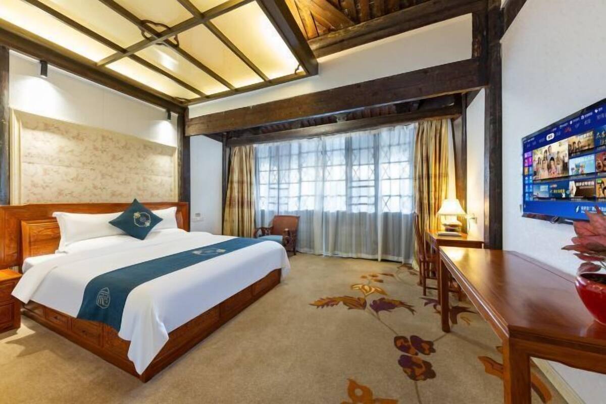 Una habitación de hotel con una cama, un escritorio, una silla y un televisor.