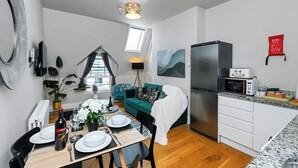 A modern kitchen with a refrigerator, microwave, and a dining area with a table set for two. - Market Street Apartment 3A Flat 4 (Nottingham)