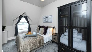 A bedroom with a bed, bedside table, lamp, and a wardrobe. - Market Street Apartment 3A Flat 4 (Nottingham)