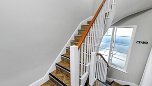 A staircase with white railings and wooden steps, a fire exit sign, and a window with a view. - Market Street Apartment 3A Flat 4 (Nottingham)