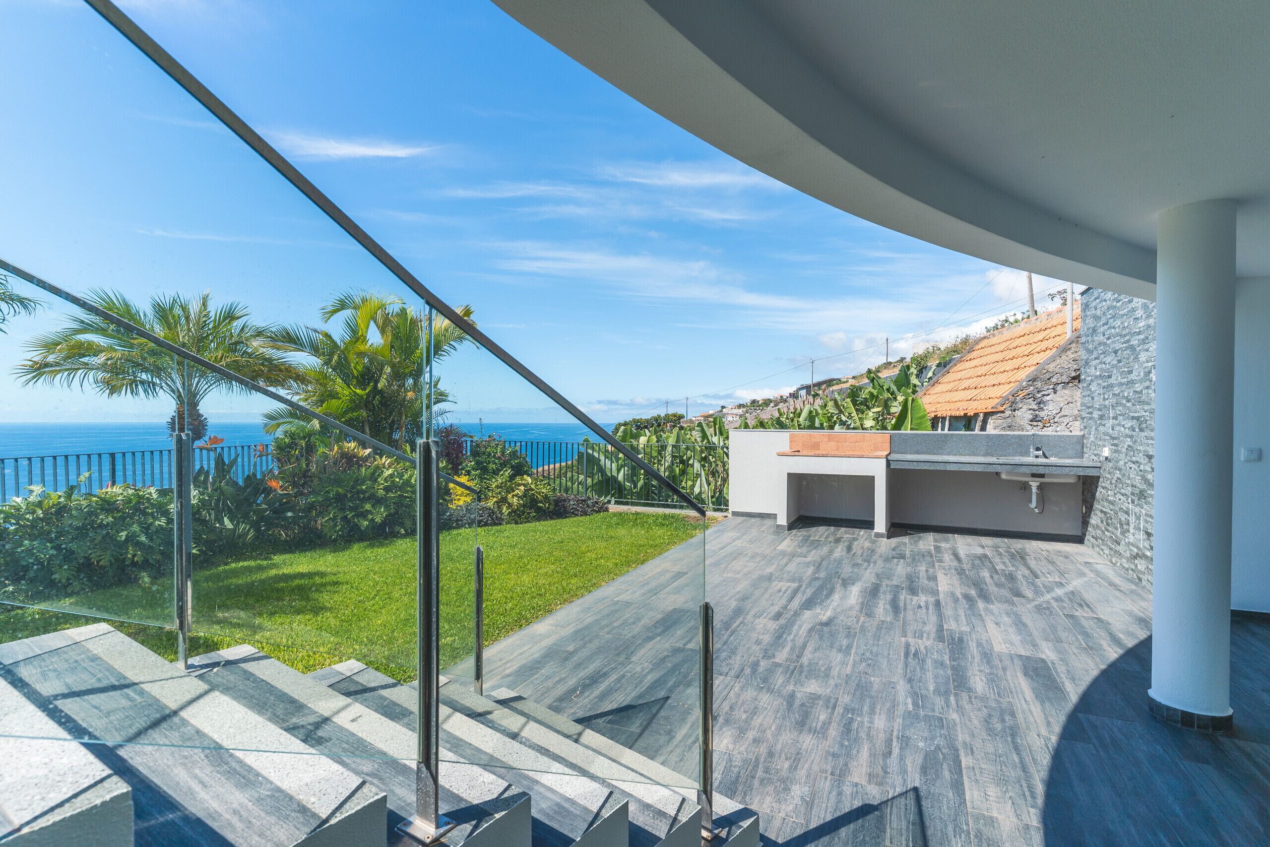 A modern outdoor area with a stone wall, a wooden deck, and a view of the ocean.
