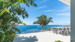 A terrace with a pool, outdoor seating, and a view of the ocean.