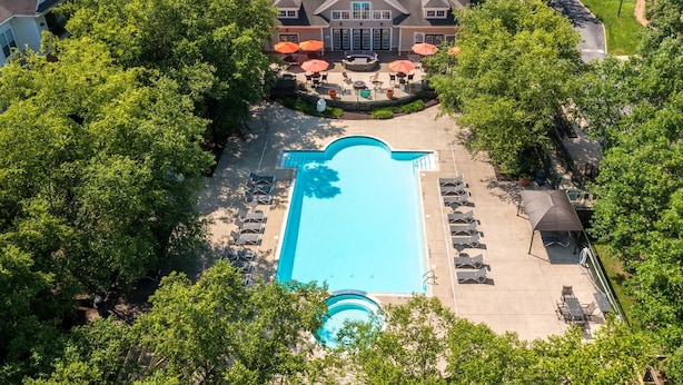 Vue aérienne d’une propriété résidentielle dotée d’une piscine, d’un espace salon extérieur et d’une grande maison avec un patio couvert.