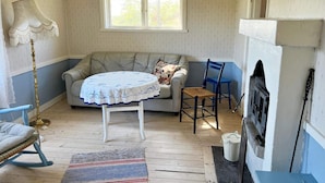 A cozy room with a sofa, a table, a chair, a lamp, and a fireplace.