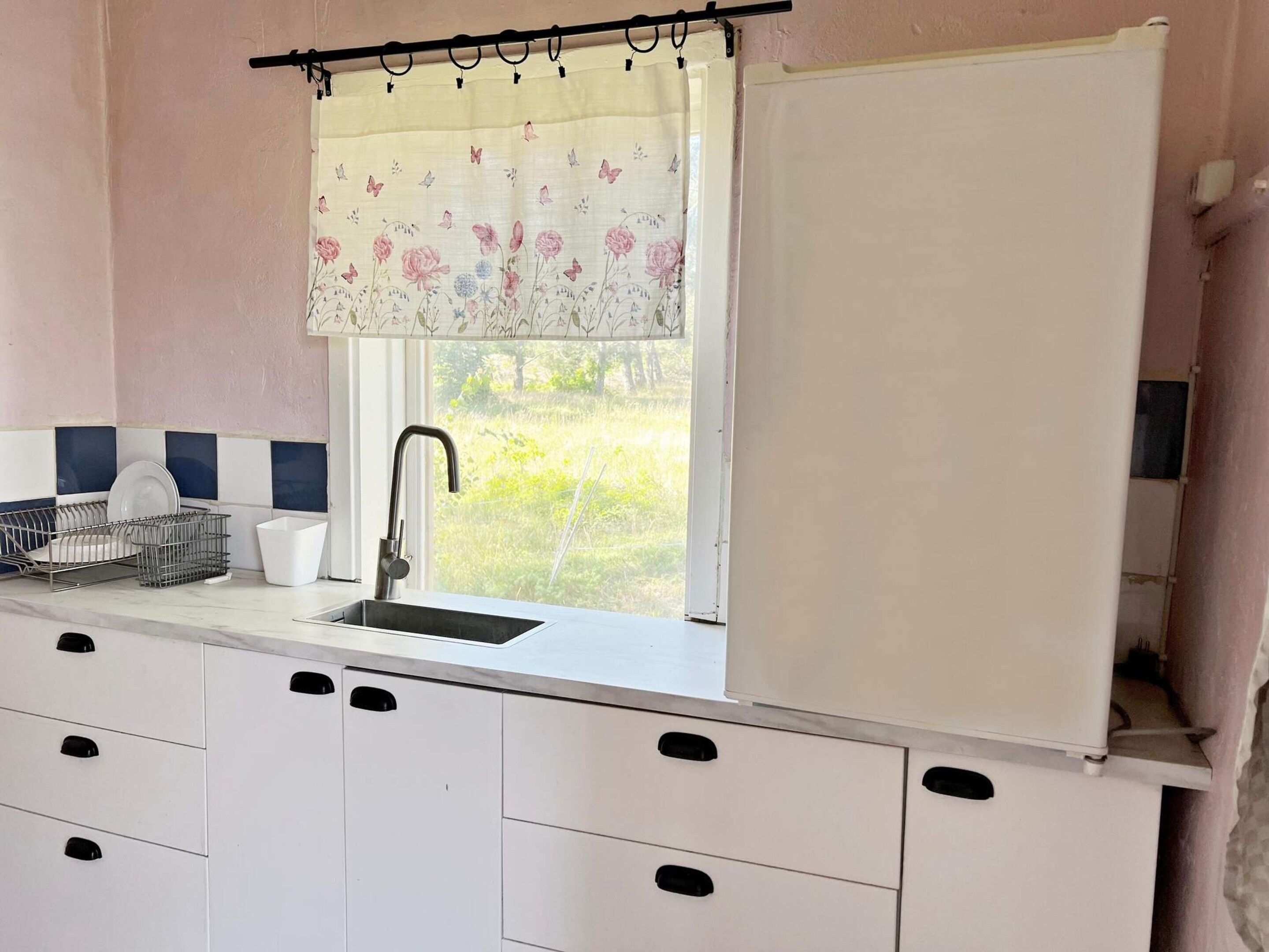 A kitchen with a window, a sink, and a dish rack.