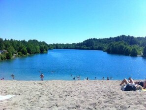 Une plage bordée d’un lac, entourée d’arbres.