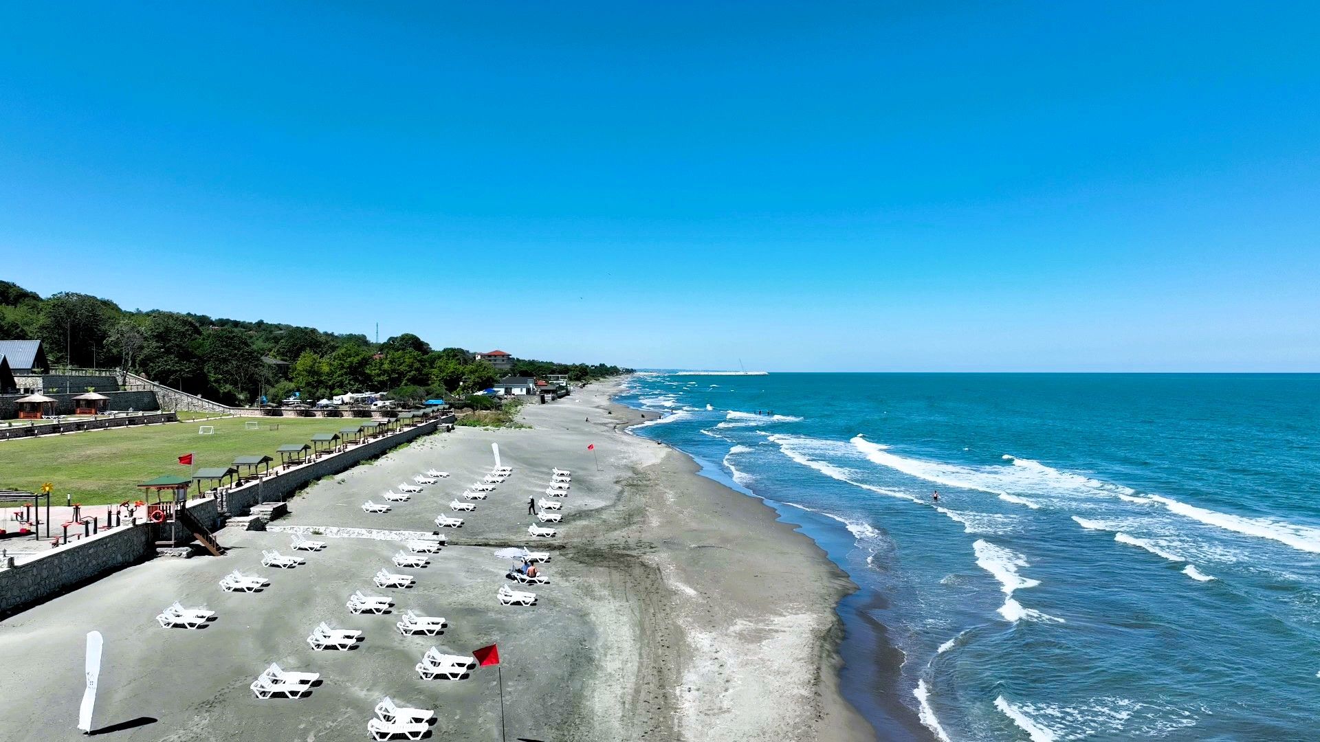 A beach with rows of sun loungers and a clear view of the ocean.