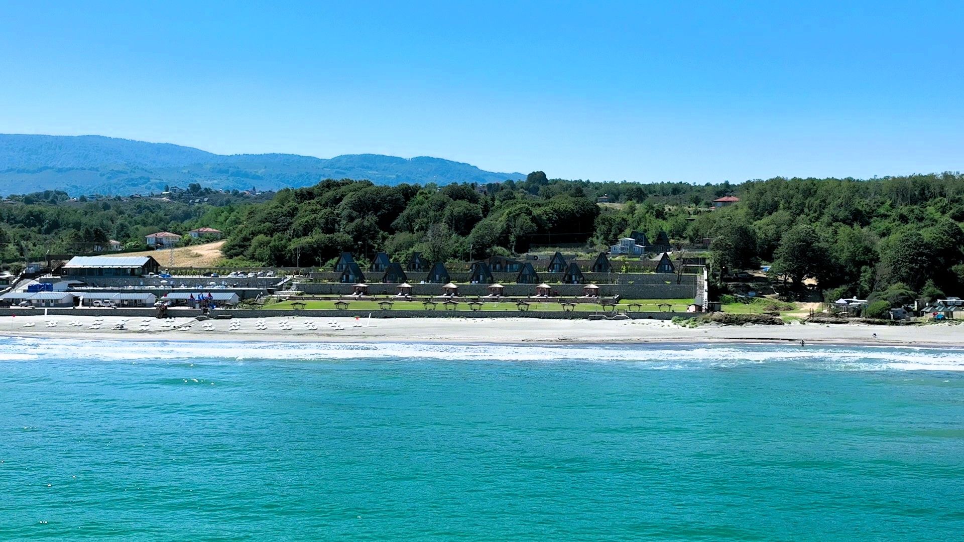 A coastal hotel with beach access, a pool area, and a view of the sea.