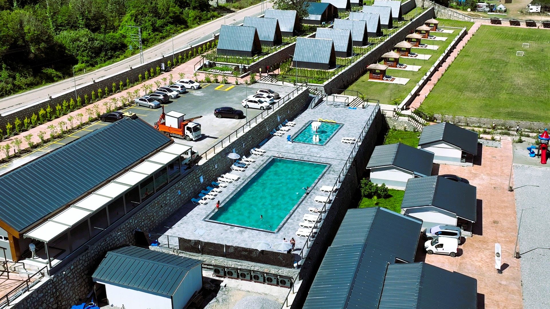 A resort with multiple swimming pools, a parking area, and a road in the background.