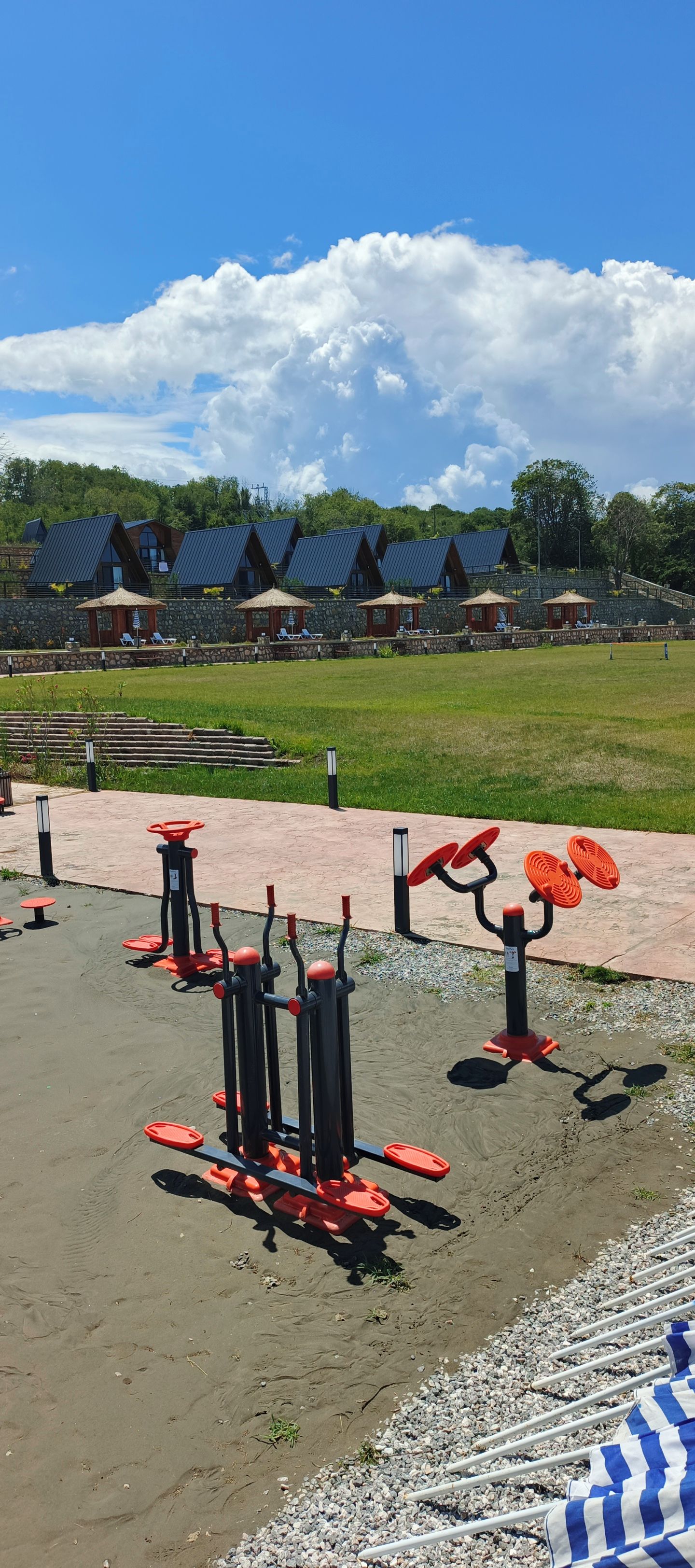 Outdoor exercise equipment, a paved walkway, and a row of buildings with sloped roofs.