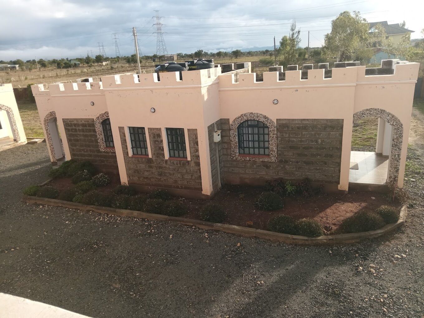A building with a beige facade, multiple windows, and a small garden area.