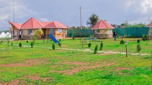 A playground with slides and a fenced area, surrounded by buildings with red roofs. - Enkapune Cowboy park resort (Kajiado)