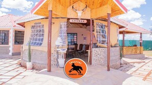 A wooden building with a sign reading "Lounge" and a logo for "Cowboy Park" in front. - Enkapune Cowboy park resort (Kajiado)