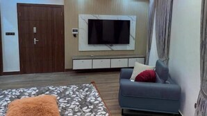 Un salon moderne avec un canapé, un téléviseur fixé au mur et un tapis à motifs.