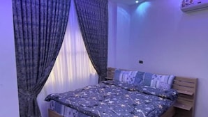 A bedroom with a bed, curtains, a ceiling light, and an air conditioning unit.