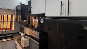 A modern kitchen with white cabinets, a black refrigerator, and a stove.