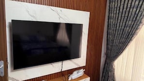 A TV mounted on a marble wall with a wooden panel and a curtain.