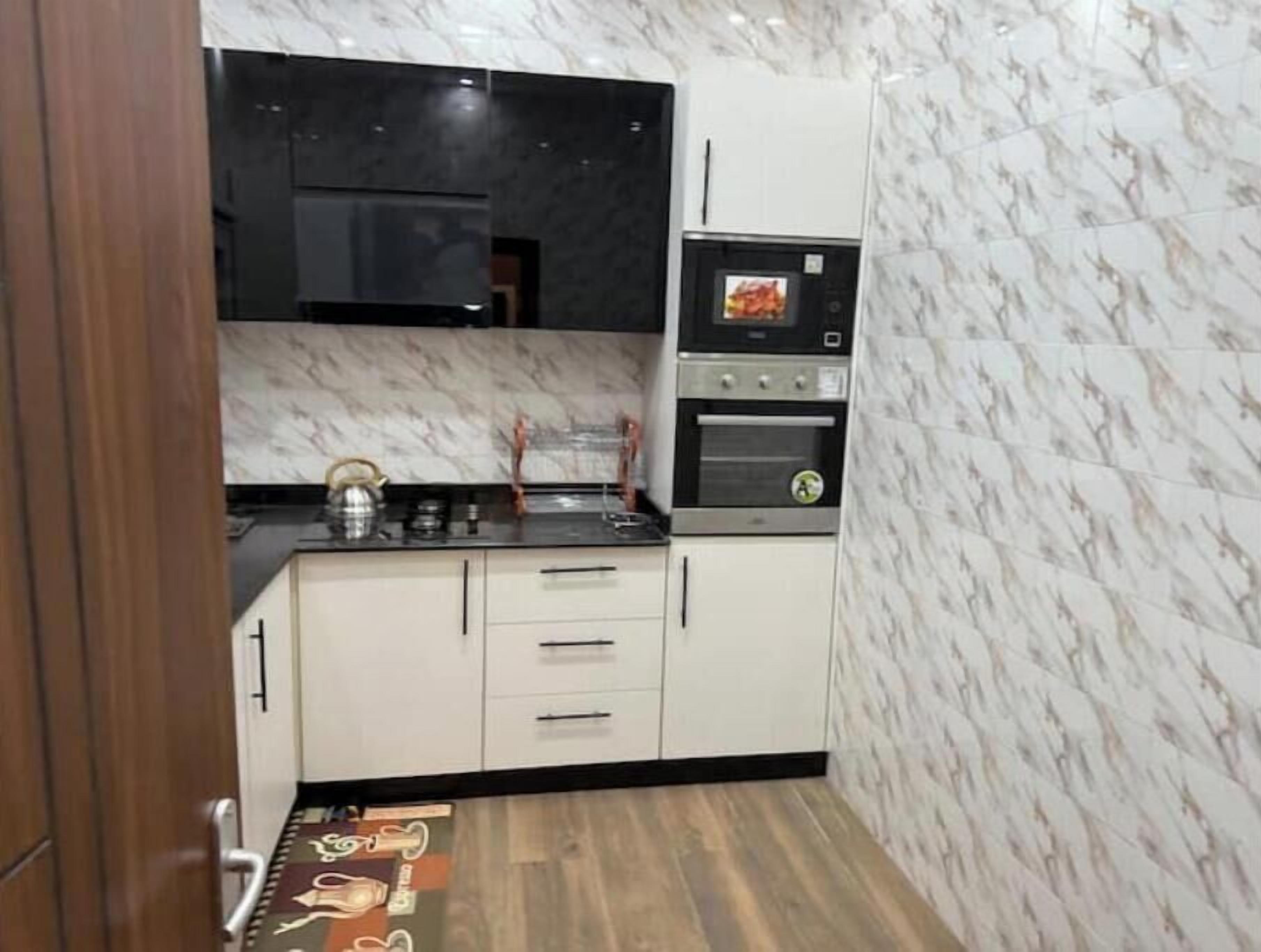 Una cucina compatta con mobili bianchi, un piano di lavoro nero e un forno integrato.