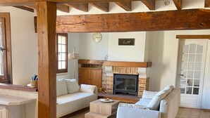 Ein gemütliches Wohnzimmer mit Kamin, Holzbalken und bequemen Sitzmöglichkeiten.