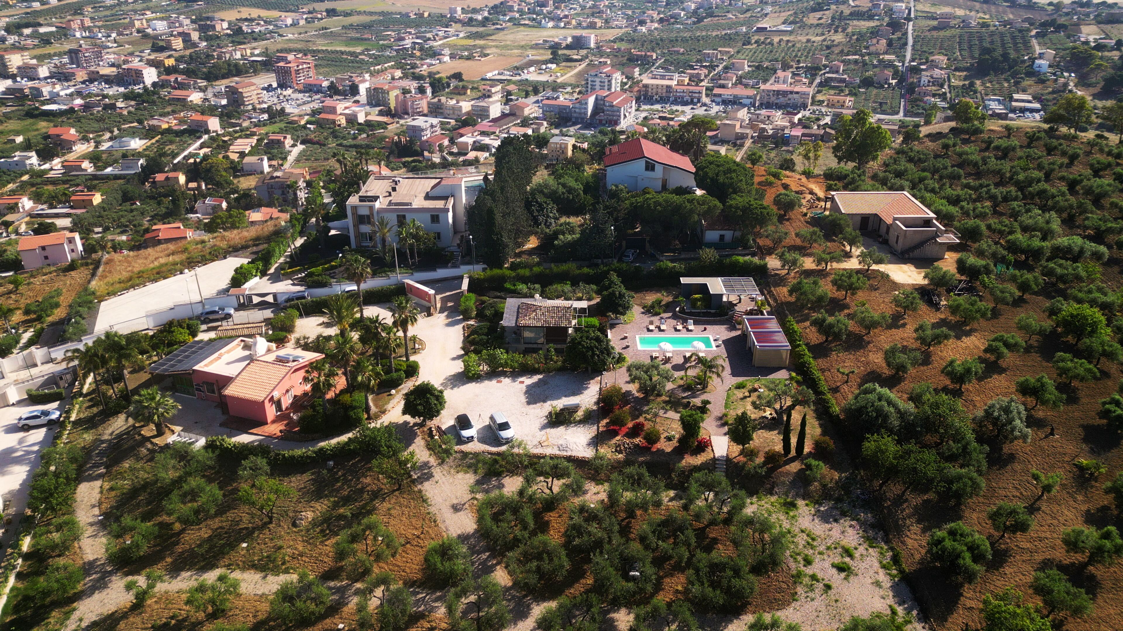 Una vista aerea di un quartiere residenziale con diverse case, una piscina e pannelli solari.