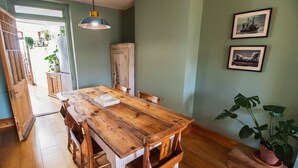 A dining area with a wooden table, chairs, and a hanging light fixture. - Sun House Apartment Seaford (Seaford)