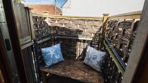A wooden bench with two pillows, surrounded by a woven fence. - Sun House Apartment Seaford (Seaford)