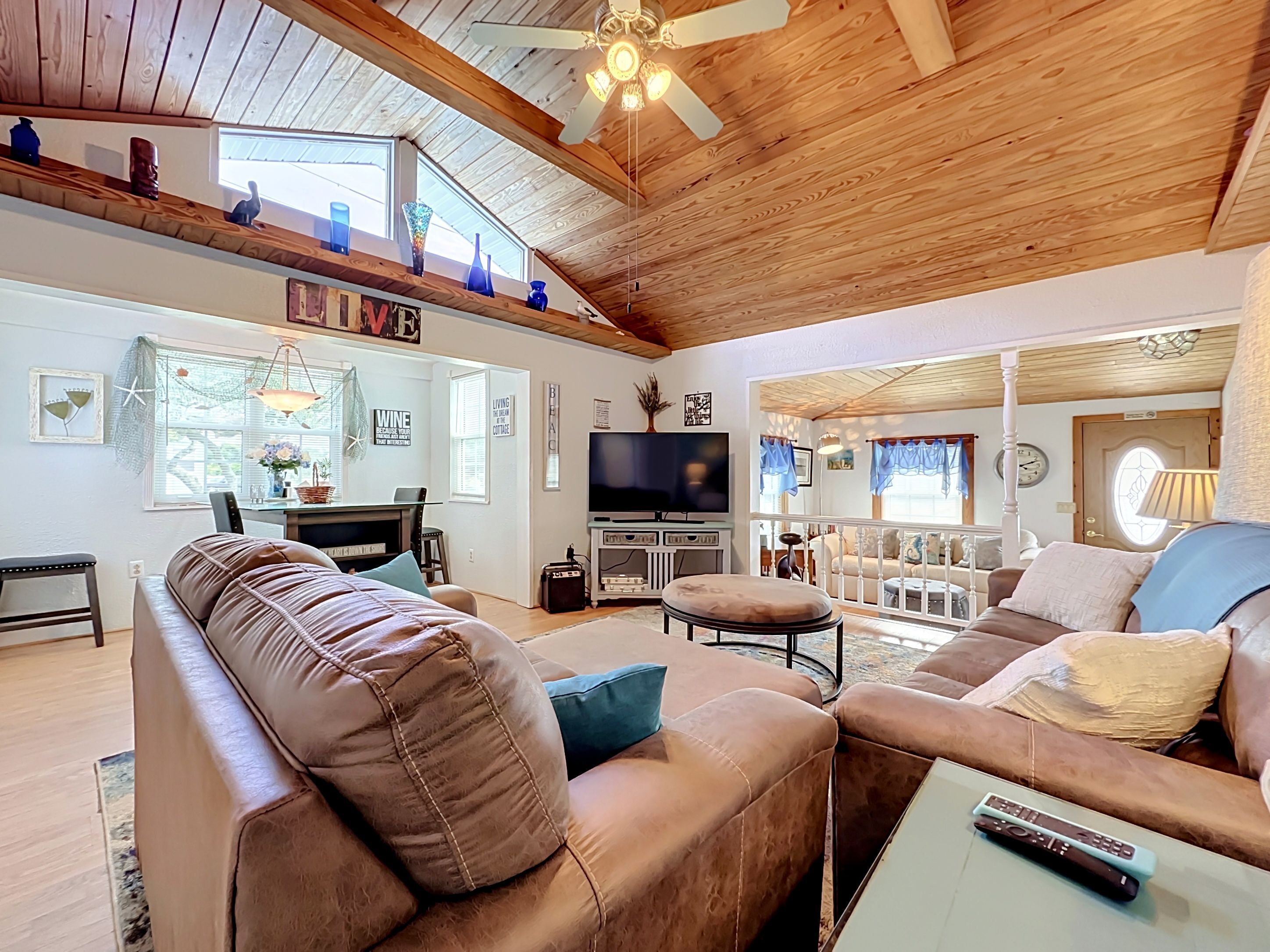 A spacious living room with a high ceiling, wooden beams, a television, and a cozy seating area.