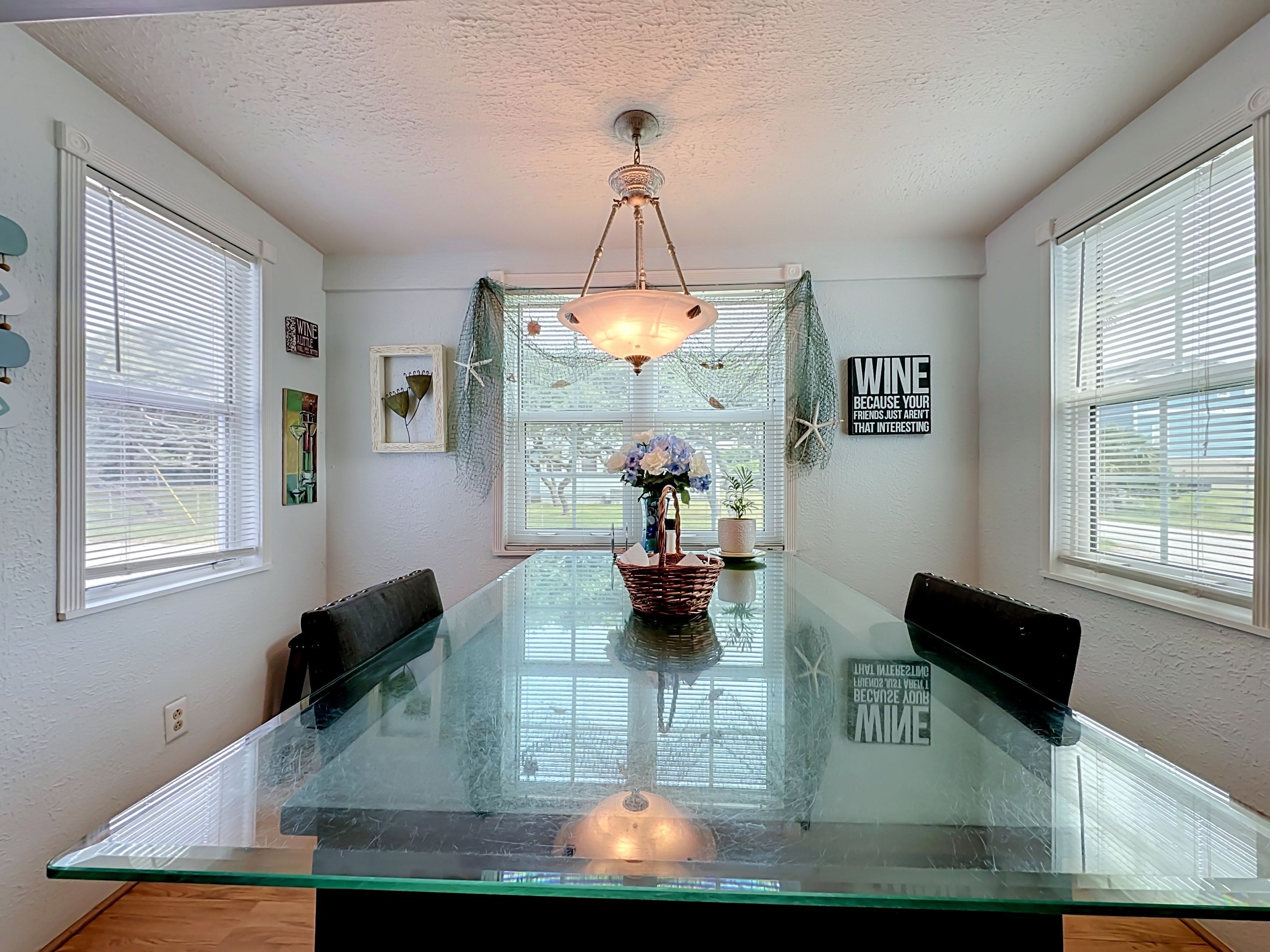 Een eethoek met een glazen tafel, stoelen, een kroonluchter en decoratieve objecten aan de wanden.