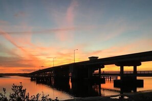A bridge over calm water during sunset with a clear sky.