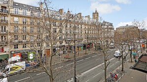 A street view with multi-story buildings, a pharmacy, and parked bicycles.