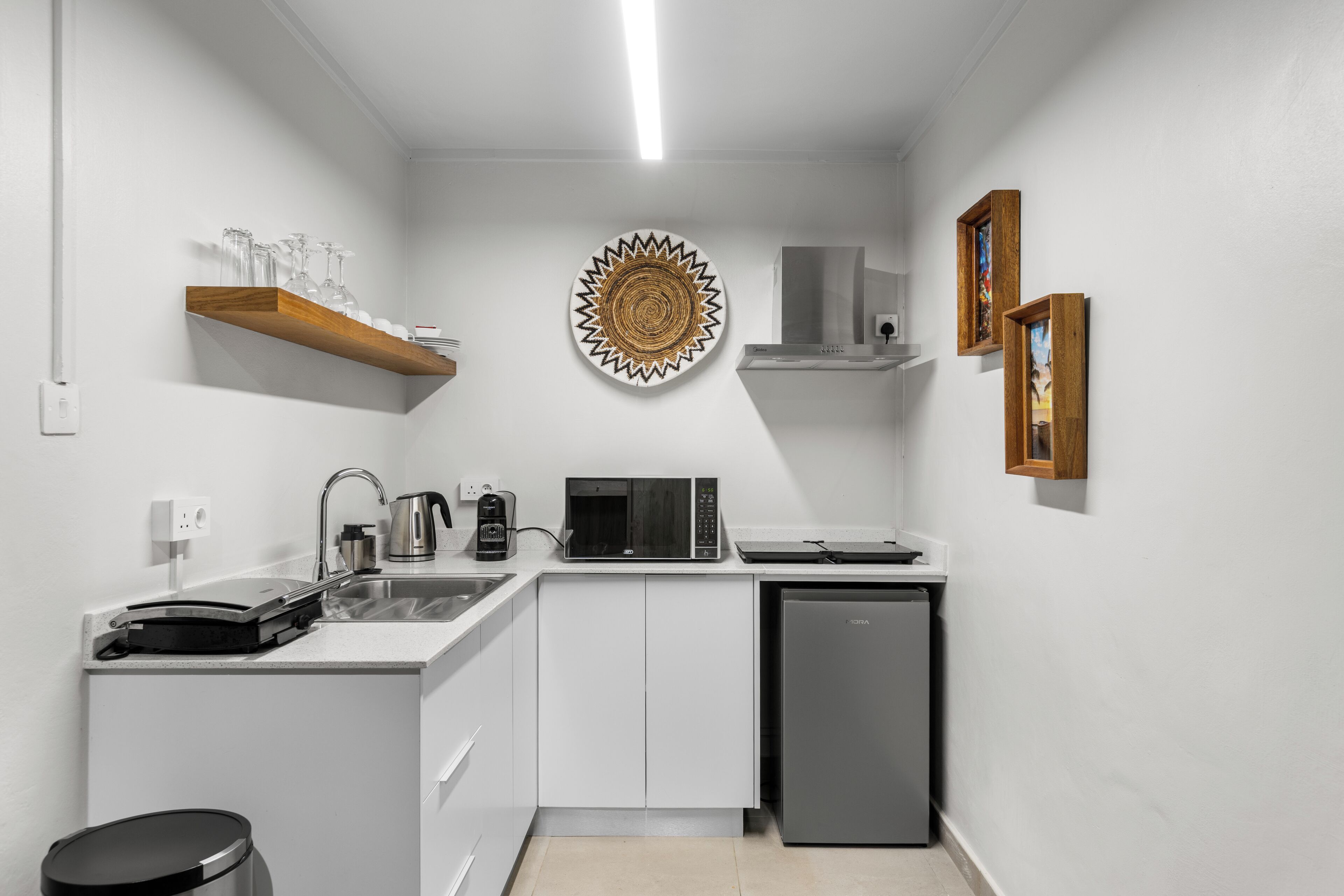 A compact kitchen with white cabinetry, a microwave, a coffee maker, and a dishwasher.