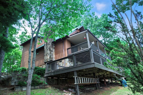 Une cabane en rondins dotée d’un balcon et d’une fondation en pierre.