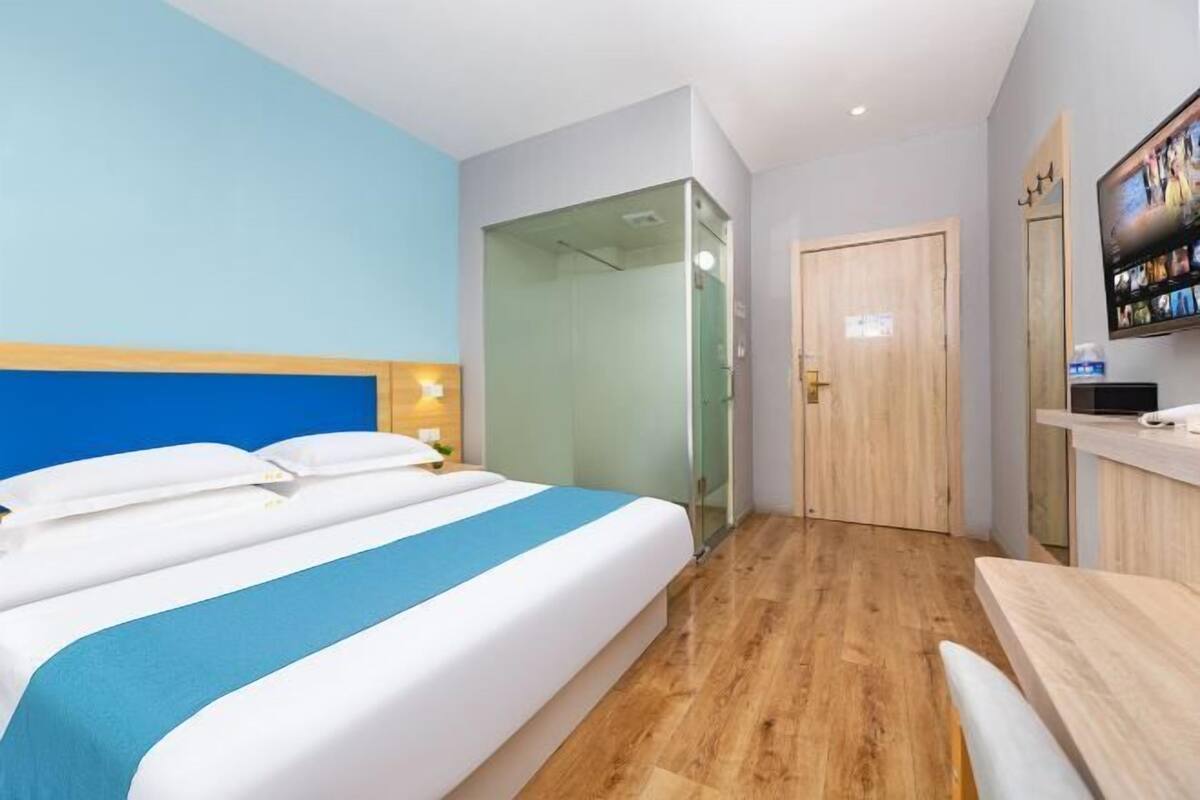 Ein Hotelzimmer mit einem Bett, einem Schreibtisch, einem Fernseher und einer Tür.