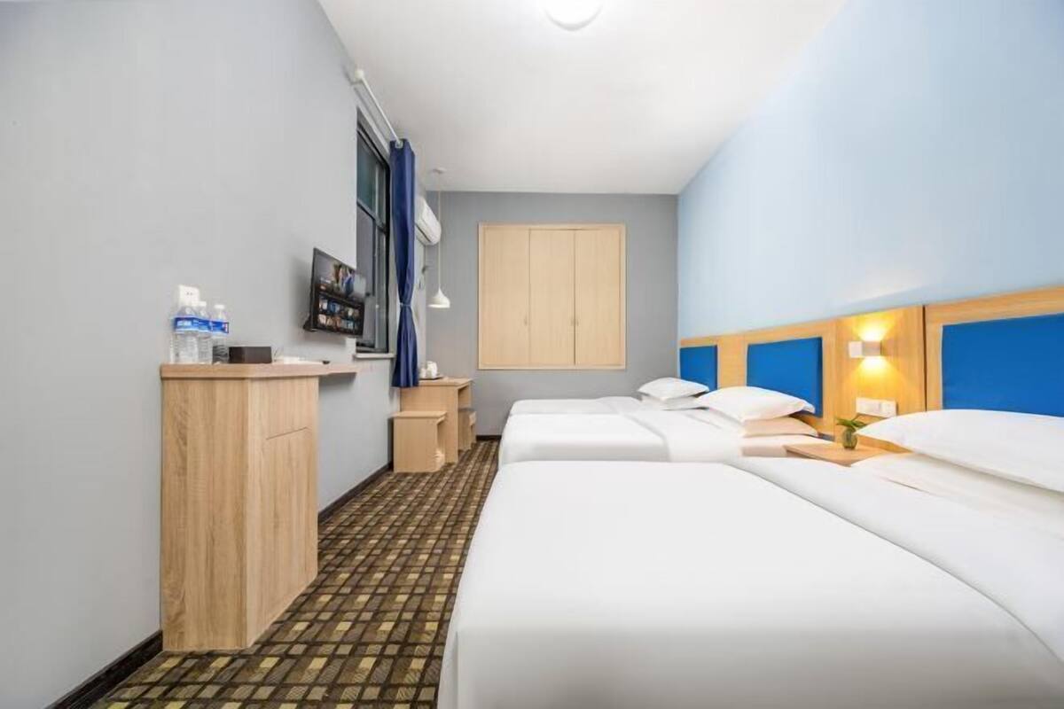 Ein Hotelzimmer mit Bett, Nachttischen, einem Kleiderschrank, einem Spiegel und einem Fernseher.