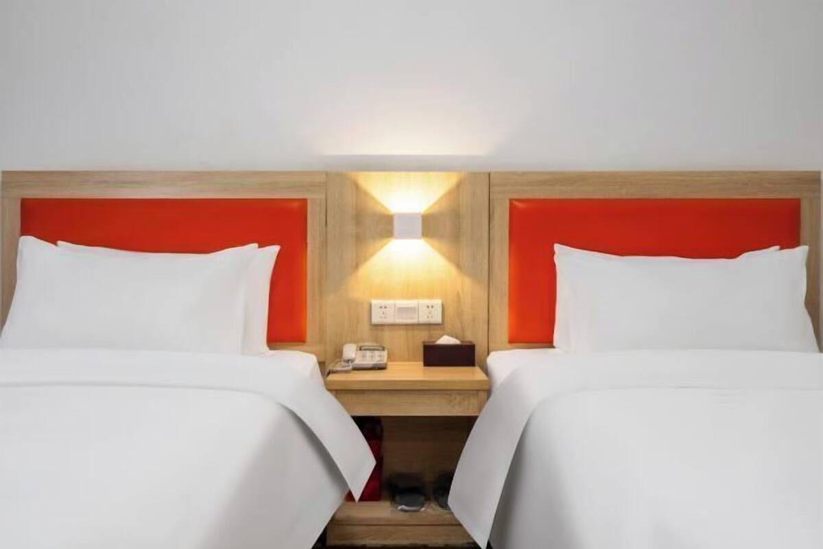 Ein Hotelzimmer mit zwei Betten, einem hölzernen Kopfteil, einem Nachttisch mit Lampe und einem Telefon.