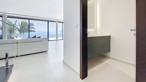 A modern interior with a large window, a sofa, and a minimalist bathroom. - Villa Zenha in Ribeira Brava (Ribeira Brava)