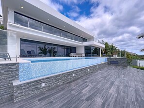 A modern two-story house with a swimming pool, large windows, and a stone wall. - Villa Zenha by Atlantic Holiday (Ribeira Brava)