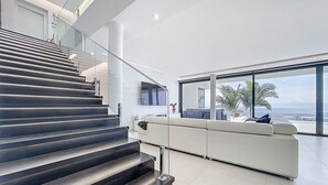A modern interior with a staircase, a sofa, and a view of the ocean. - Villa Zenha in Ribeira Brava (Ribeira Brava)